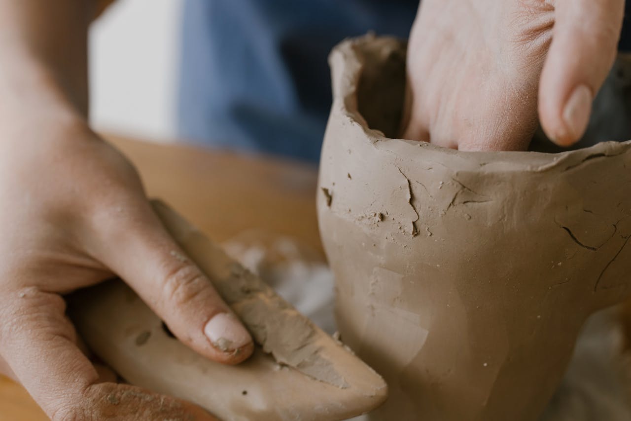 Close-up of hands shaping a clay pot, showcasing the art of pottery making.