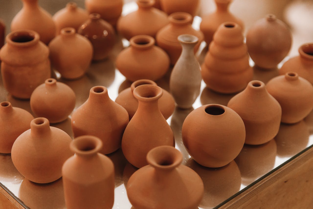 A variety of ceramic pottery displayed on a glossy surface, showcasing craftsmanship.